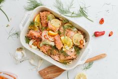 a casserole dish filled with salmon, lemons, and dill pickles