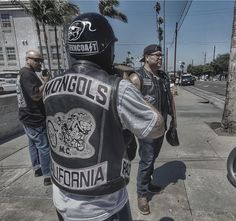 a group of men walking down a street next to palm trees