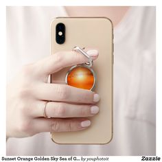 a woman is holding up her phone case with an orange sun in the center on it