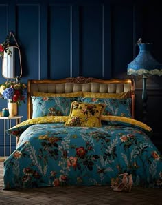 a bedroom with blue walls and floral bedding in the corner, along with a lamp