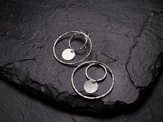 These lovely drop earrings feature a textured 3/8 inch (10mm) sterling silver disc dropped off a 5/8 inch (15mm) hammered sterling silver circle, inside a larger, 1.5 inch (40mm) hammered sterling silver circle hoop. All the different circular parts give these particular hoops extra fun movement. The hooks are also sterling silver and come secured with soft clear rubber stoppers. All the silverwork is handcrafted by me in my studio using traditional silversmithing tools like a torch and hammer. Handmade Silver Circular Earrings, Silver Hammered Round Earrings, Minimalist Sterling Silver Round Disc Earrings, Silver Hammered Open Circle Earrings, Hammered Circle Sterling Silver Earrings, Hammered Sterling Silver, Dangly Earrings, Earrings Inspiration, Minimalist Jewelry