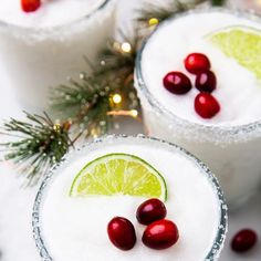 two margaritas with cranberries and lime on the rim are garnished with sugar