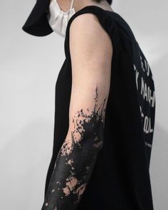 a person with a black and white tattoo on their arm, wearing a black shirt