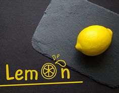 a lemon sitting on top of a slate cutting board next to a stone sign that says lemon