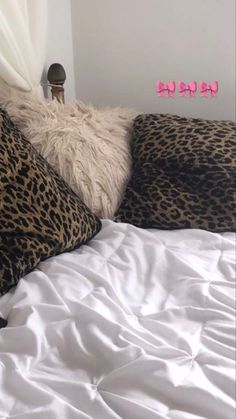 a leopard print pillow on top of a white bed