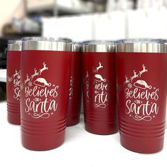 four red tumblers sitting on top of a table with santa's sleigh