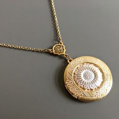 "White Sunflower Locket Necklace - Antiqued Gold and White Plated Sunflower attached to Antiqued Gold and White plated Locket with a pretty floral design.  The locket dangles from an Antiqued Gold plated Flower Connector. The Locket is approximately 30 mm (1.25\") in diameter. Antiqued Gold plated Chain For other sunflower designs:  https://www.etsy.com/shop/mcstoneworks/search?search_query=sunflower&order=date_desc&view_type=gallery&ref=shop_search For other locket designs: http://www.etsy.com/ Gold Flower Necklace With Vintage Charm, Vintage Gold Necklaces With Flower Shape, Vintage Gold Flower Shaped Necklace, Vintage Gold Flower Necklace For Wedding, Vintage Jewelry With Flower Charm And Pendant, Vintage Flower Charm Pendant Jewelry, Vintage Flower-shaped Nickel-free Necklaces, Vintage Medallion Jewelry With Flower Charm, Vintage Flower Necklaces For Anniversary