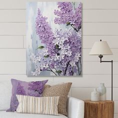 a living room with a white couch and purple flowers on the wall in front of it