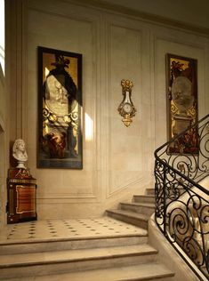 an ornate staircase with two paintings on the wall