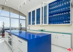 a large kitchen with blue counter tops and white cabinetry, along with floor to ceiling windows