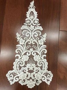 a white lace christmas tree decoration on a wooden floor with wood floors in the background