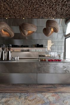 the interior of a restaurant with stainless steel counter tops and hanging lights over it's bar area