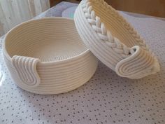 two white baskets sitting on top of a table next to each other with braided handles