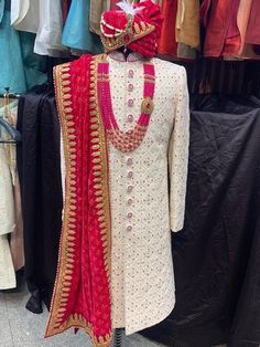 a mannequin dressed in white and red stands next to other clothing on display