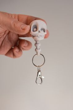 a hand holding a skeleton keychain with a skull on it's back