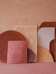 several different shapes and sizes of plates against a pink wall