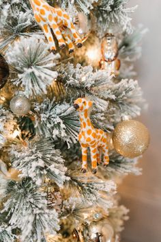 a giraffe ornament is hanging on a christmas tree with gold ornaments