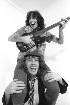 two people with guitars on their heads and one person holding the guitar over his head