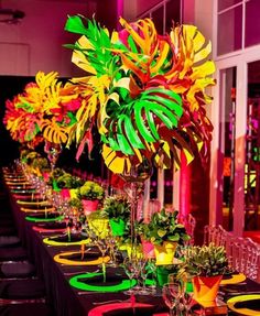 a long table is set up with colorful flowers and place settings for an event or party