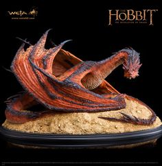 an orange dragon statue sitting on top of a wooden table next to a black background