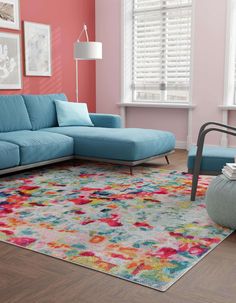 a living room with pink walls, blue couches and colorful rug on the floor