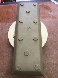 a piece of pottery sitting on top of a wooden table next to a white plate