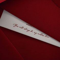 a piece of paper with writing on it sitting on top of a red cloth covered surface