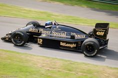 a man driving a race car on a track with grass in the backgroud