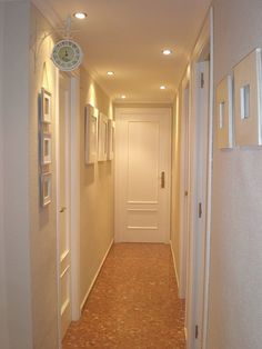 an empty hallway with white doors and framed pictures on the wall next to each other