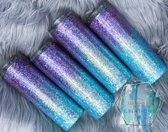 four blue and purple glitter candles sitting on top of a white fur covered floor next to each other