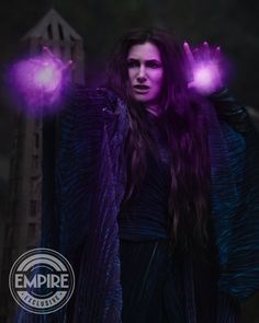 a woman with long hair and purple gloves holding two glowing hands in front of her