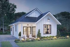 a small white house with lots of windows and lights in the front yard at night