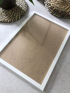 a white frame sitting on top of a table next to a potted green plant