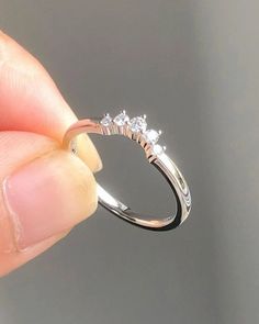 a person is holding a ring with three diamonds on the top and bottom half of it