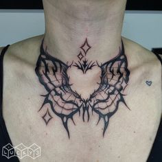 a woman's neck is adorned with an intricate tattoo design and heart shaped wings