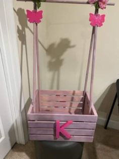 a pink wooden swing with flowers on it and the letter k painted on the bottom