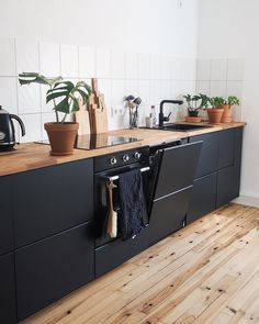 a kitchen with wooden floors and black cabinets