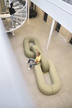 two people sitting on giant inflatable sofas at the bottom of a spiral staircase