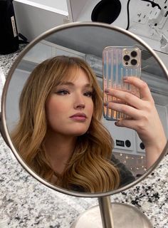 a woman taking a selfie in front of a bathroom mirror with her cell phone