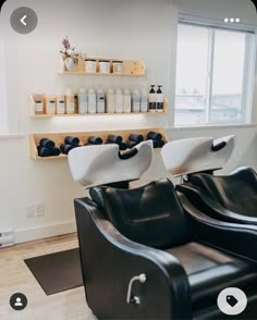 two black chairs sitting in front of a window with bottles on the wall behind them