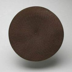 a brown woven bowl sitting on top of a white table