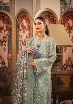 Pakistani Wedding Dress in Sage Green Shade is a stunningly made ensemble with unmatched and exquisite decorations on it rendering it look awe-inspiring and jaw-dropping. This Pakistani Wedding Dress is adorned with luxurious embroidered patterns canvasing the entire dress and turning it into a sight to behold. Kameez: This Pakistani Wedding Dress comes with a beautiful kameez in premium quality organza. This kameez is decorated with fine embroidery work that is even more prominent and holds the Green Pakistani Dress, Green Salwar Kameez, Dress Name, Embellished Shirt, Organza Sleeves, Pakistani Wedding Dress, Pakistani Fancy Dresses, Pakistani Salwar Kameez, Embroidered Organza