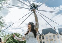 a woman in a white wedding dress holding up a large piece of fabric to the sky