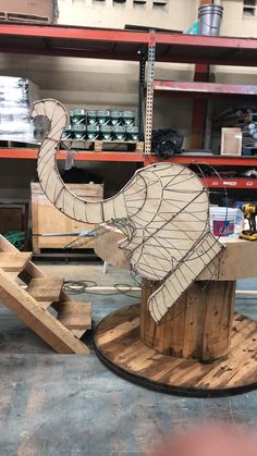 an elephant sculpture sitting on top of a wooden stand in a warehouse next to shelves