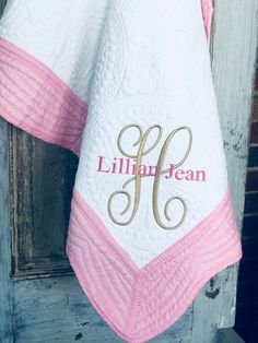 a white and pink towel hanging on a door with monogrammed name written on it