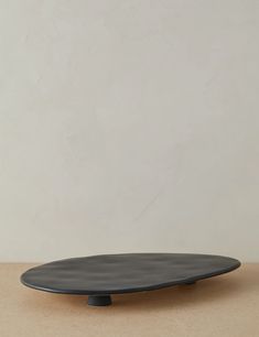 a black plate sitting on top of a table next to a white wall and floor