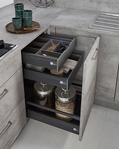 an open drawer in the middle of a kitchen with spices and other items on it