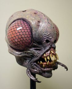 an alien head is shown on top of a stand with its mouth open and teeth out