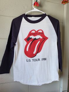 This extremely rare baseball-style tee from the Rolling Stones' 1981 US tour is now yours to own! It is in good condition, with no damage other than natural wear with age. Size is 80s adult medium. Retro Raglan Sleeve T-shirt With Graphic Print, Retro T-shirt With Screen Print For Baseball Season, Retro Screen Print T-shirt For Baseball Season, Vintage Graphic Print T-shirt For Baseball Season, Retro Graphic Print T-shirt For Baseball Season, Vintage Tops With Letter Print For Baseball Season, Vintage Baseball Fan Merchandise T-shirt, Vintage Baseball Season Fan Merchandise T-shirt, Retro Baseball Fan Merchandise Tops