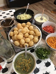 a table topped with bowls filled with different types of food next to plates and spoons